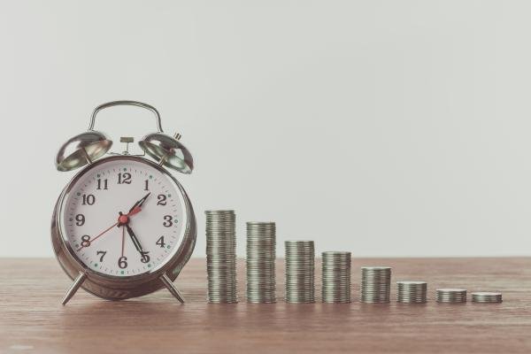 Reloj y monedas en un acomodo que simula una gráfica.