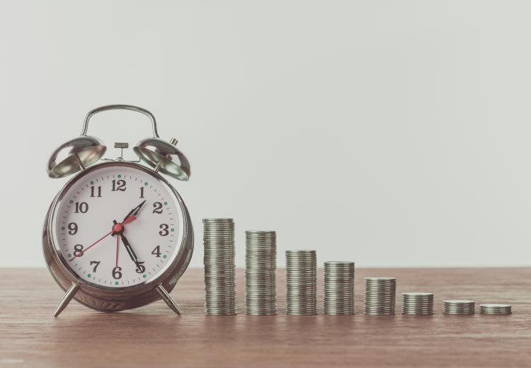 Reloj y monedas en un acomodo que simula una gráfica.